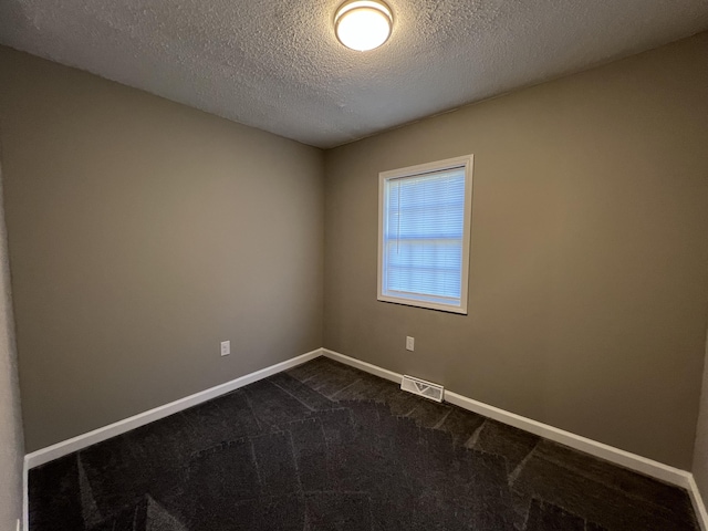 carpeted empty room featuring a textured ceiling