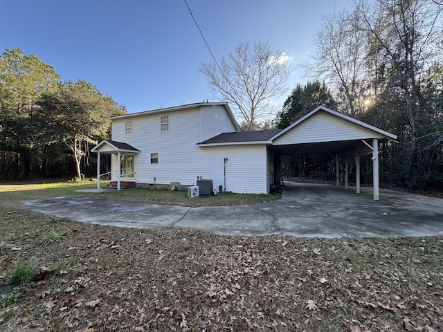 back of house with central air condition unit and a carport