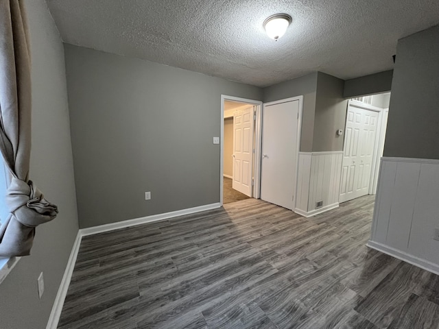 empty room featuring a textured ceiling and dark wood-type flooring