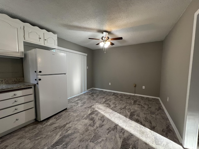 kitchen featuring a textured ceiling, white fridge, white cabinetry, and ceiling fan