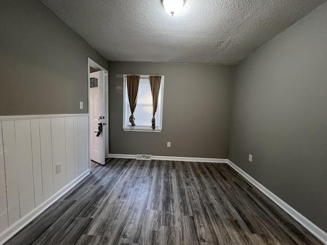 empty room featuring dark wood-type flooring and a textured ceiling