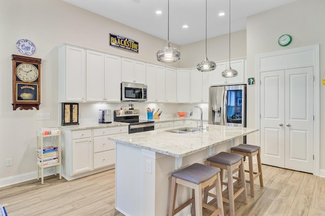5078 Song Sparrow Way, Summerville, SC 29483 - kitchen with appliances with stainless steel finishes, a sink, light wood-style flooring, white cabinets, and a breakfast bar