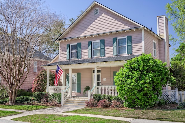 view of front facade with covered porch, a chimney, and a front lawn