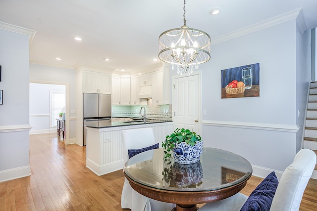 dining space with baseboards, ornamental molding, a chandelier, and light wood-type flooring