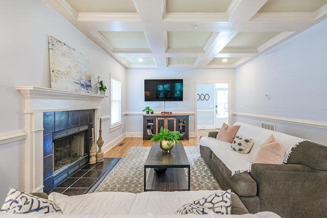 living area featuring coffered ceiling, a tiled fireplace, beam ceiling, wood finished floors, and baseboards
