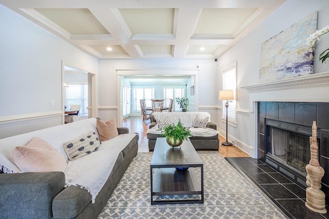 living area featuring a tile fireplace, crown molding, baseboards, beam ceiling, and coffered ceiling