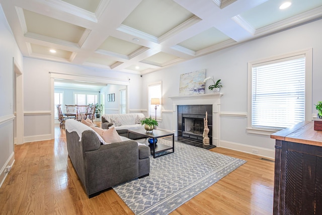 living area with light wood finished floors, baseboards, a tiled fireplace, beam ceiling, and coffered ceiling