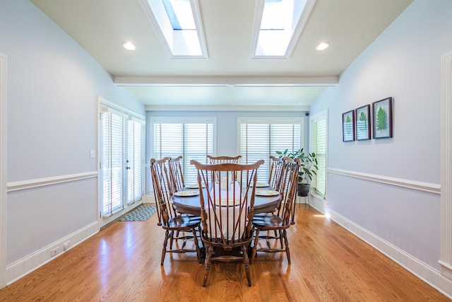 dining space featuring vaulted ceiling with skylight, baseboards, light wood-style floors, and recessed lighting