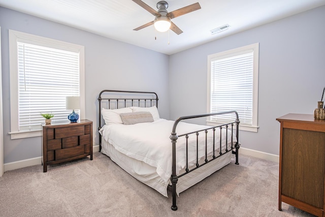 bedroom with baseboards, visible vents, a ceiling fan, and light carpet