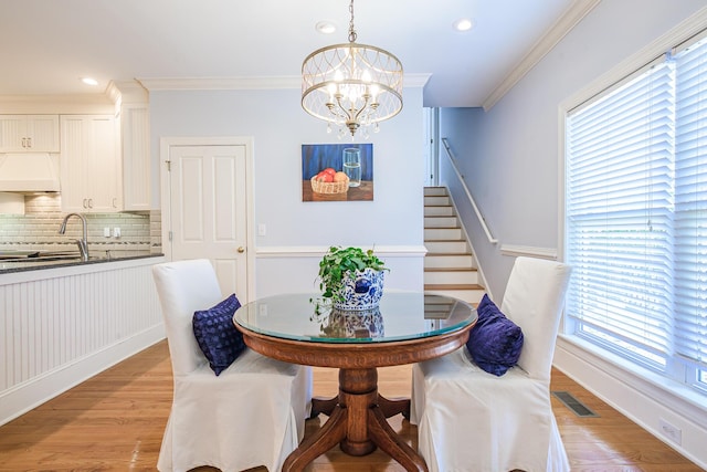 dining room with stairs, a notable chandelier, light wood-style flooring, visible vents, and ornamental molding
