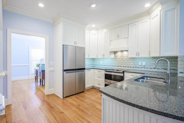 kitchen with a sink, light wood-style floors, premium range hood, and appliances with stainless steel finishes