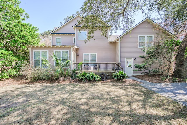back of property with a deck and a lawn