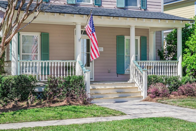 entrance to property featuring covered porch and roof with shingles