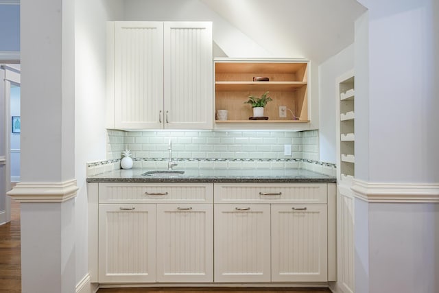 kitchen featuring decorative backsplash, a sink, open shelves, and stone countertops
