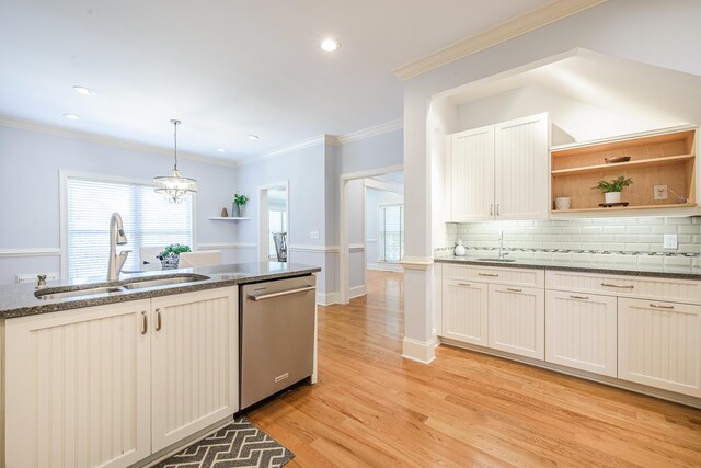 kitchen featuring dark stone countertops, stainless steel dishwasher, backsplash, a sink, and light wood-style flooring