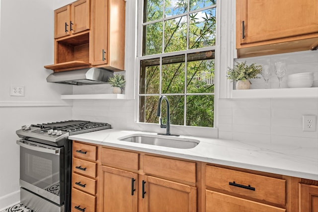 kitchen with decorative backsplash, sink, stainless steel gas range, light stone countertops, and range hood