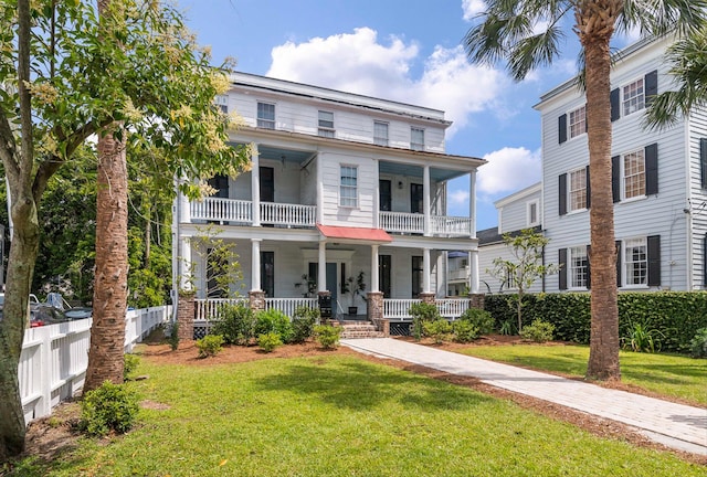 view of front facade featuring a front lawn, a balcony, and covered porch