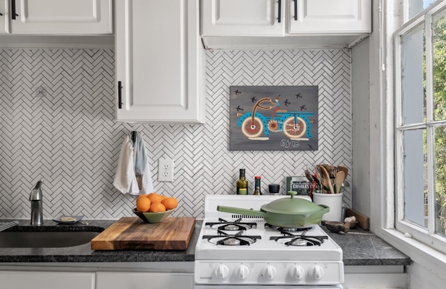 kitchen featuring gas range gas stove, white cabinets, sink, and decorative backsplash