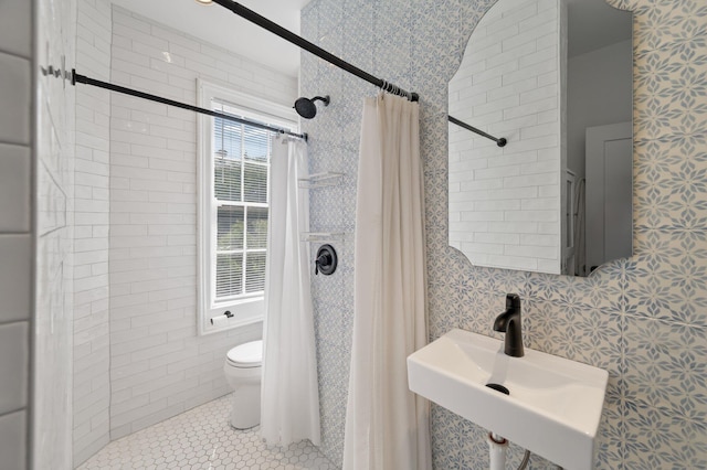 bathroom with walk in shower, sink, tile patterned floors, toilet, and tile walls