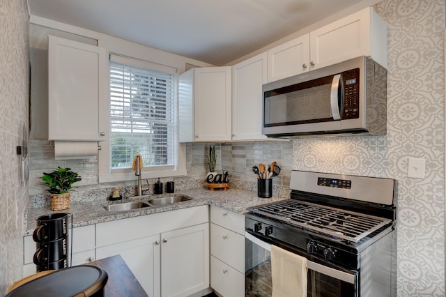 kitchen featuring white cabinets, sink, light stone counters, and stainless steel appliances