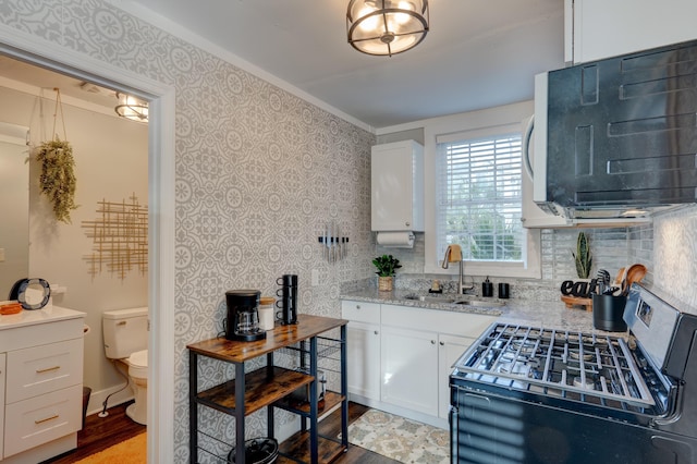 kitchen featuring white cabinetry, sink, stainless steel range oven, and light wood-type flooring