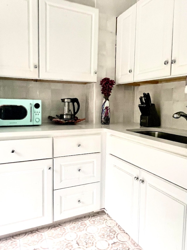 kitchen with tasteful backsplash, white cabinetry, and sink