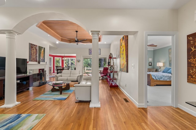 2105 Loblolly Ln, Seabrook Island, SC 29455 - living room with a ceiling fan, ornate columns, light wood-style flooring, a tray ceiling, and baseboards