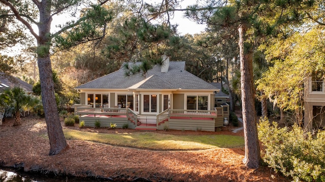 2105 Loblolly Ln, Seabrook Island, SC 29455 - view of front facade with roof with shingles, a deck, a chimney, a front yard, and a sunroom