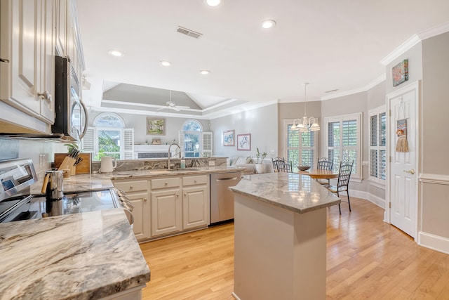 kitchen featuring light stone countertops, appliances with stainless steel finishes, a kitchen island, ceiling fan with notable chandelier, and light wood-type flooring