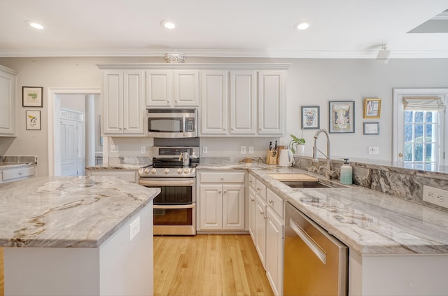 kitchen featuring light stone countertops, appliances with stainless steel finishes, white cabinetry, and sink