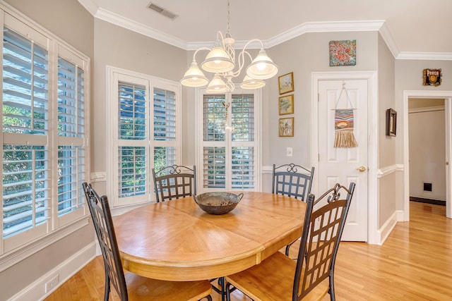 dining space with a chandelier, crown molding, and light hardwood / wood-style floors