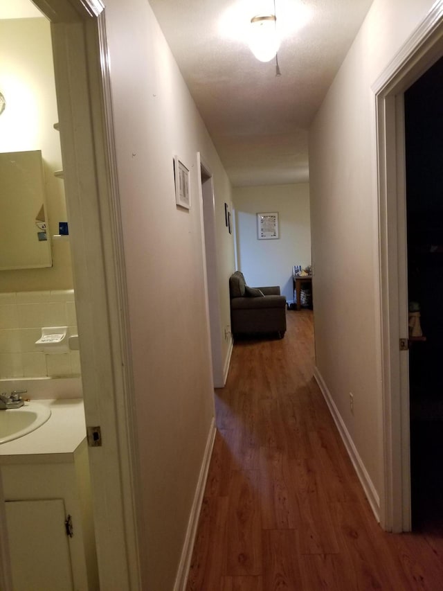 corridor with dark wood-type flooring and sink