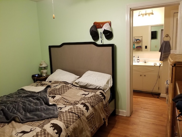 bedroom featuring light hardwood / wood-style flooring and connected bathroom