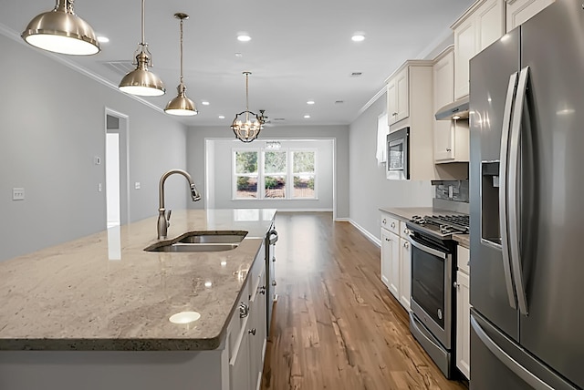 kitchen featuring a kitchen island with sink, sink, decorative light fixtures, and appliances with stainless steel finishes