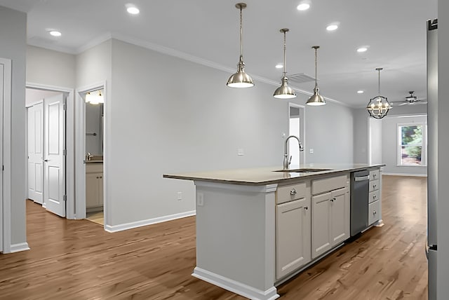 kitchen with hanging light fixtures, ceiling fan, a kitchen island with sink, and sink