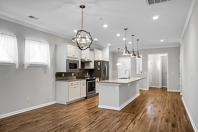 kitchen with white cabinets, appliances with stainless steel finishes, decorative light fixtures, and wood-type flooring