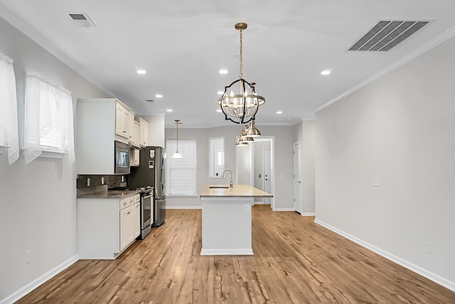 kitchen with a wealth of natural light, sink, stainless steel appliances, light hardwood / wood-style flooring, and white cabinets