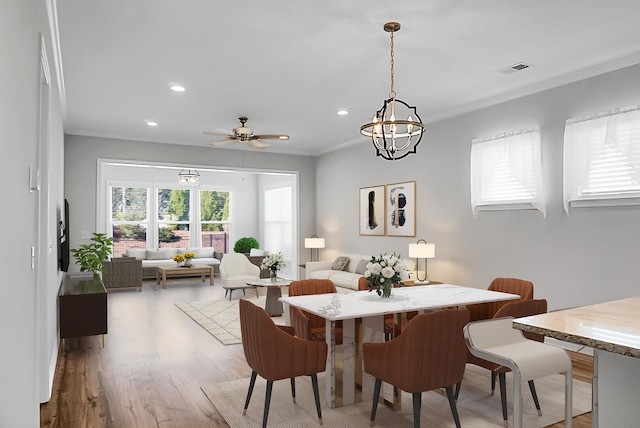 dining area featuring ceiling fan with notable chandelier, light hardwood / wood-style floors, and crown molding