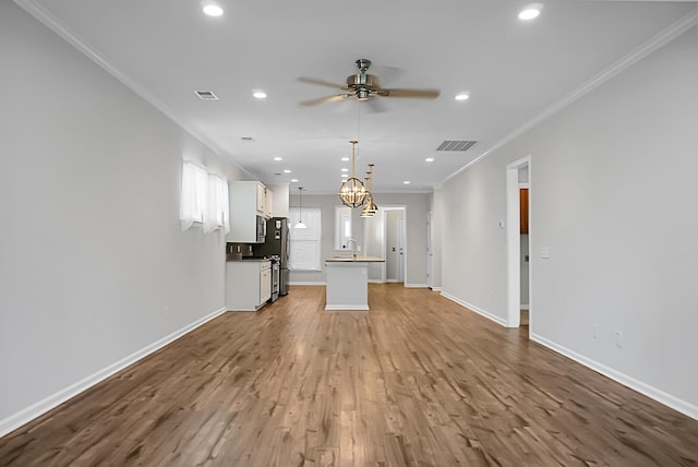 unfurnished living room with sink, hardwood / wood-style floors, ceiling fan with notable chandelier, and ornamental molding