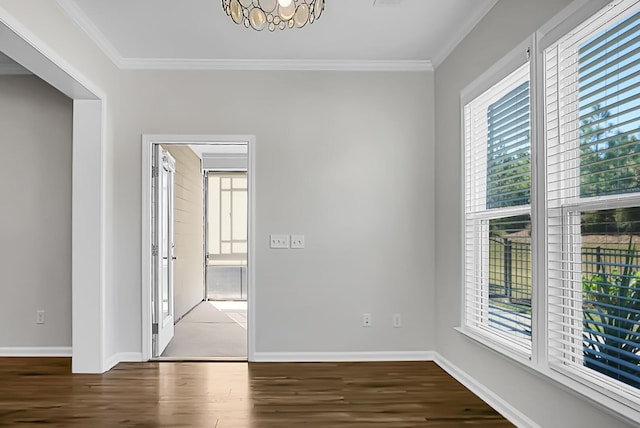 empty room featuring crown molding, dark wood-type flooring, and a chandelier