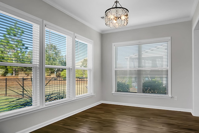 empty room featuring a notable chandelier, dark hardwood / wood-style flooring, plenty of natural light, and ornamental molding