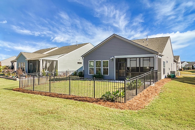 rear view of house featuring a lawn and a sunroom