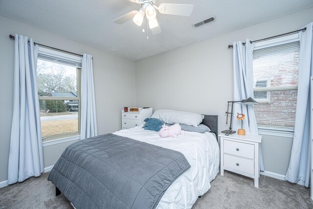 carpeted bedroom with ceiling fan and a textured ceiling