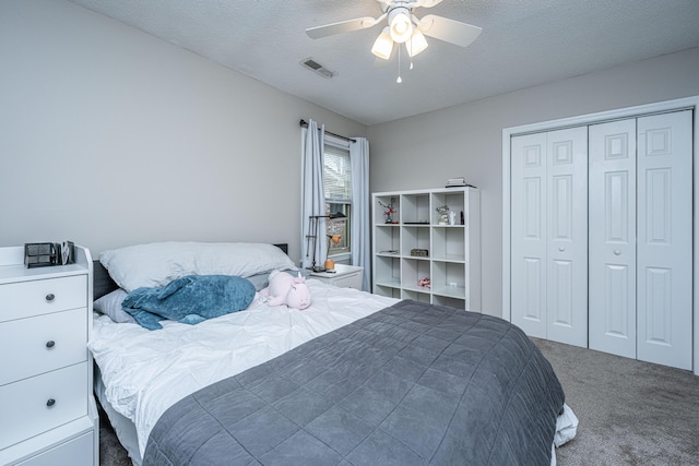 carpeted bedroom with ceiling fan, a textured ceiling, and a closet