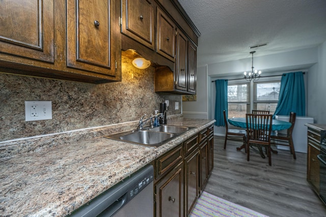 kitchen with sink, an inviting chandelier, dishwasher, light hardwood / wood-style floors, and backsplash