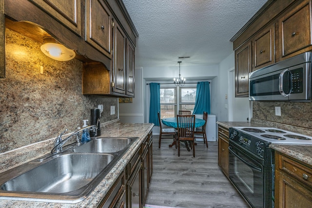 kitchen with sink, a chandelier, light wood-type flooring, black range with electric stovetop, and decorative backsplash