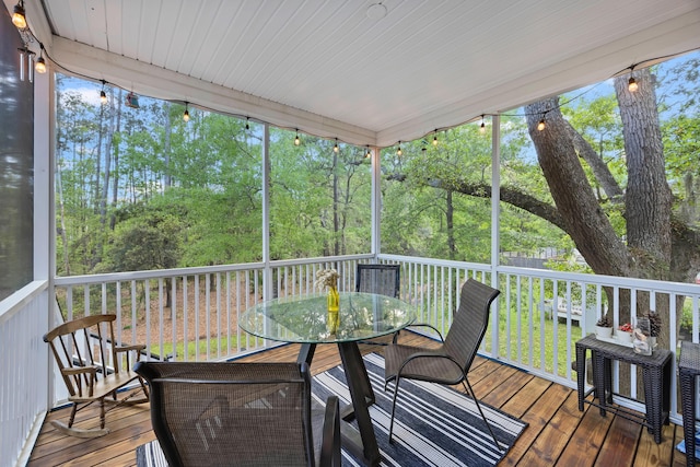 sunroom with outdoor dining area and view of scattered trees