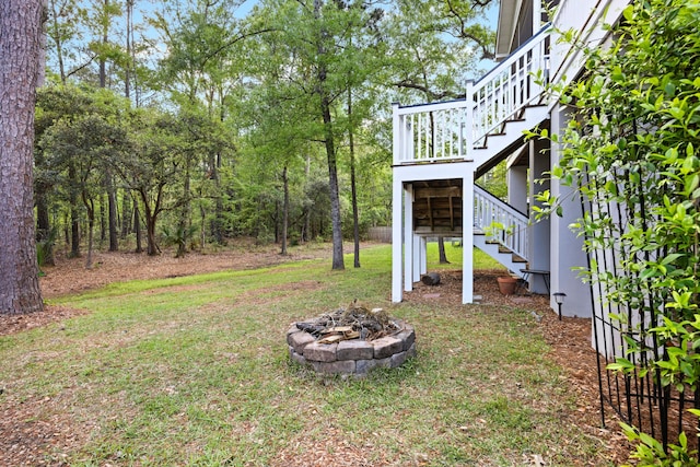 view of grassy yard with stairway and an outdoor fire pit