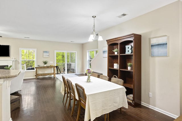 dining area featuring healthy amount of natural light, baseboards, dark wood-style flooring, and a fireplace