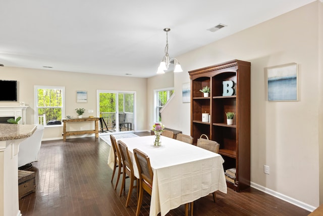 dining area featuring dark wood-style flooring, baseboards, healthy amount of natural light, and a fireplace